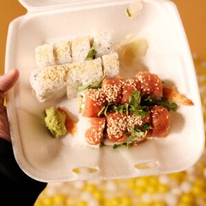 Inicio Vibrant sushi takeout with assorted rolls in a foam container, ready to enjoy.