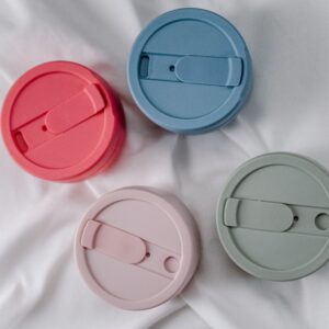 A close-up of four colorful, reusable silicone cup lids promoting zero waste.